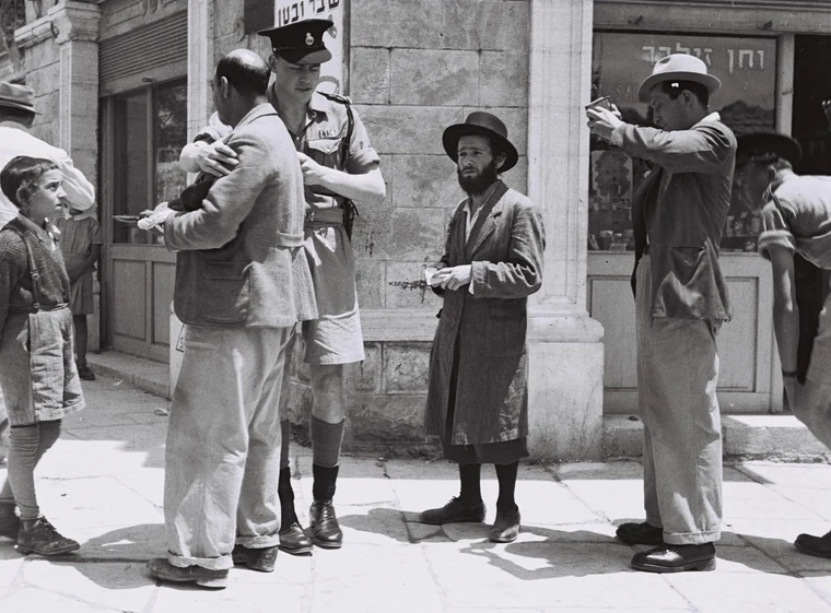 A British policeman checking papers on a street in Jerusalem during the British Mandate of Palestine, 1947