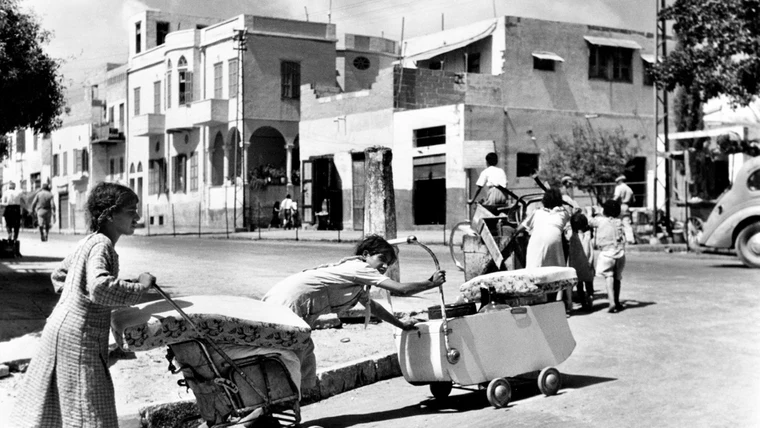 Palestinian families fleeing Jaffa in 1948, pushing belongings in prams and carts — a documentary photograph of the Nakba displacement