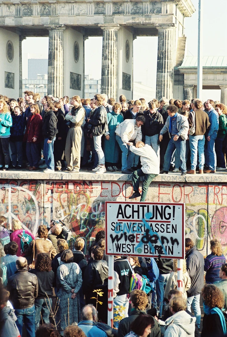 People atop the Berlin Wall near the Brandenburg Gate on 9 November 1989, celebrating the end of the Cold War