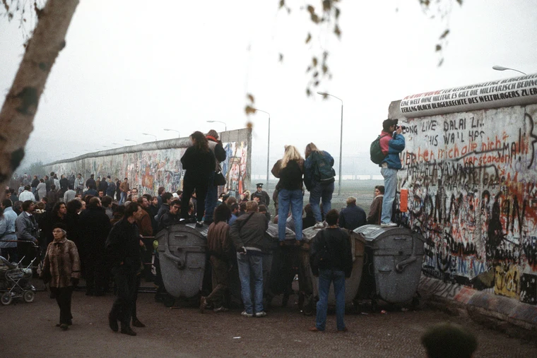 People celebrating on top of the Berlin Wall on 9 November 1989 as the Iron Curtain fell