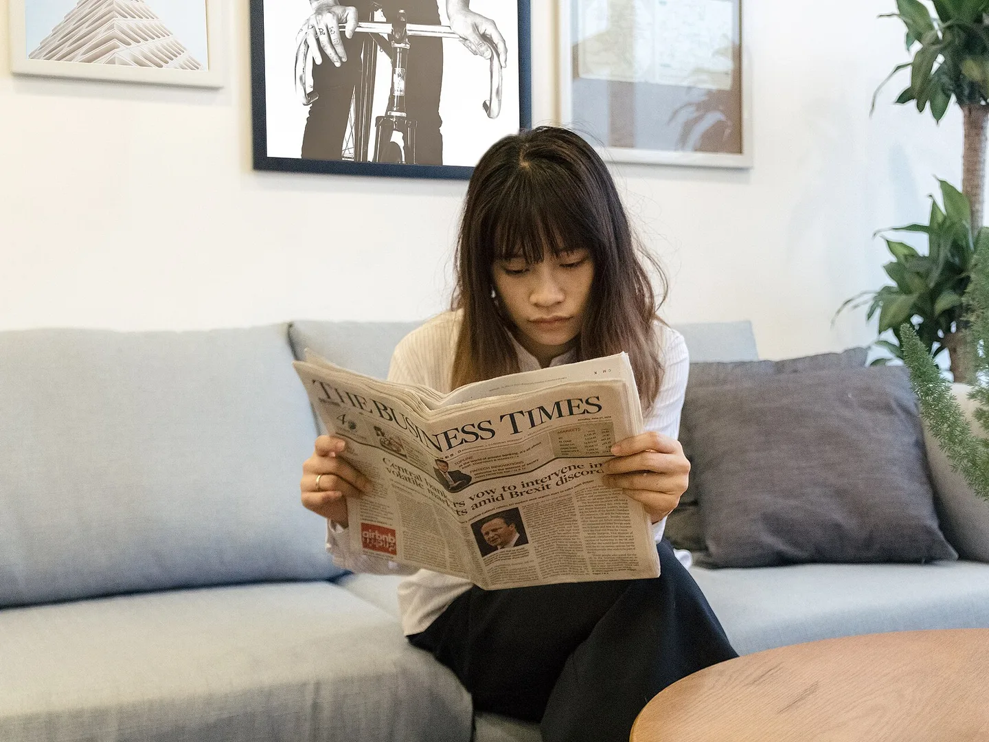 En kvinna i en soffa som läser en tidning noggrant
