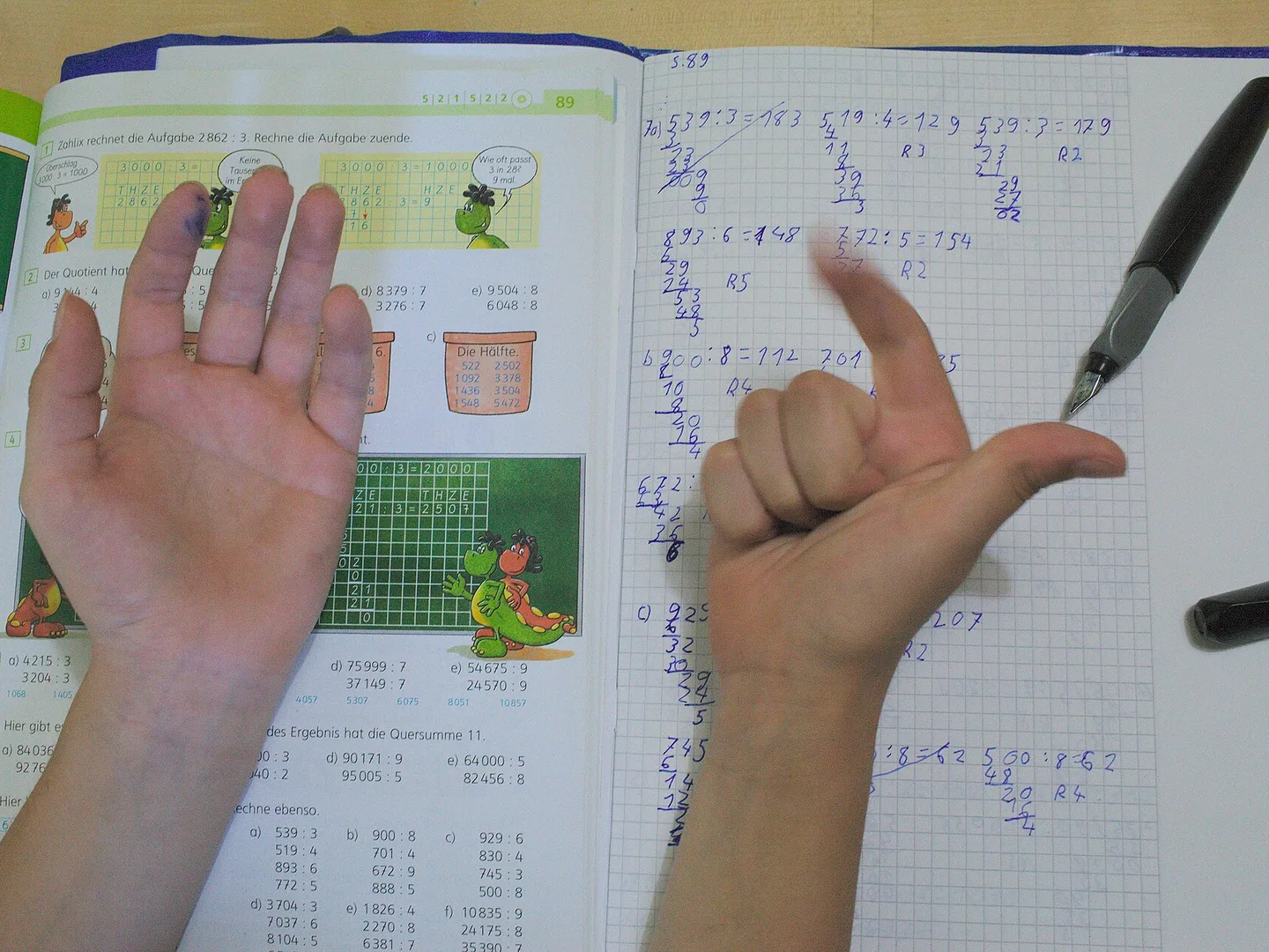 A child's hands counting on fingers over an open maths workbook